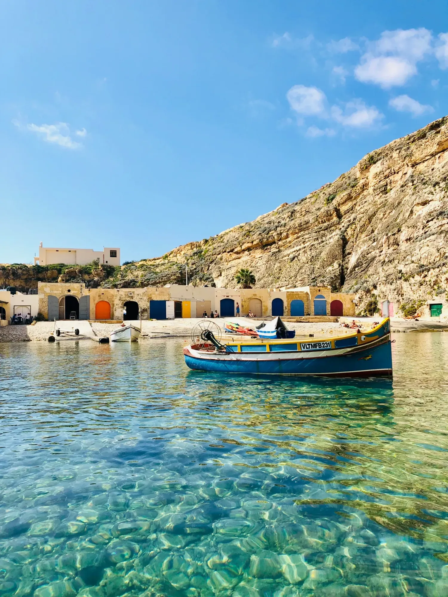 Traditional Maltese boat in a clear-water cove in Gozo